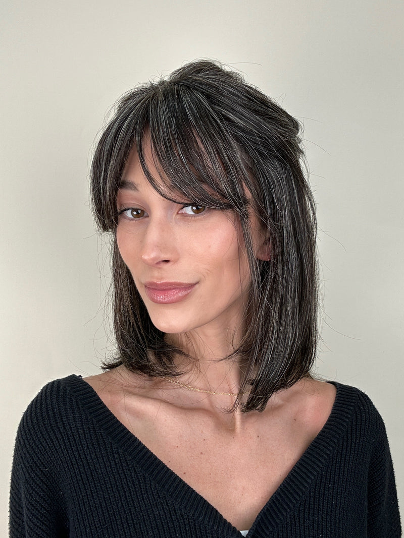 Woman with shoulder-length hair and a black top against a plain background